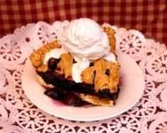 a piece of pie with ice cream on top sitting on a doily covered table