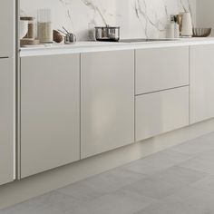 a kitchen with white cabinets and marble counter tops on the wall, along with utensils