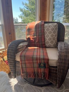 a chair that is in front of a window with a plaid blanket on top of it