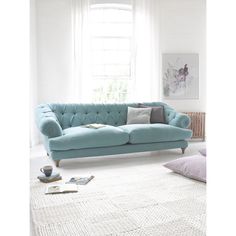 a living room with a blue couch and pillows on the floor in front of a window