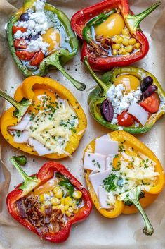 four peppers with different toppings on them sitting on top of a white tray covered in wax paper