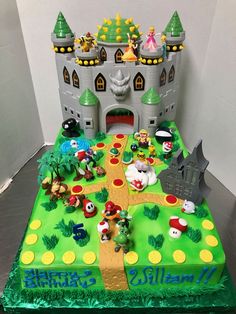 a birthday cake is decorated with mario and luigi's castle