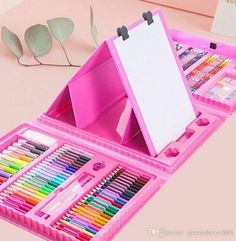 a pink box filled with lots of different colored crayons and pencils on top of a table