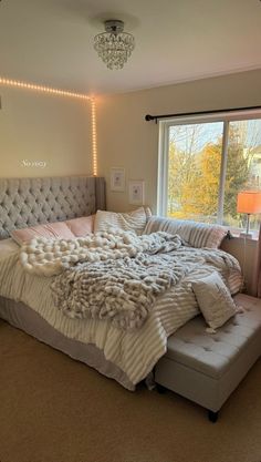 a bedroom with a large bed covered in blankets and pillows, next to a window