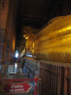 there is a large golden buddha statue in the middle of a building with no entry signs on it