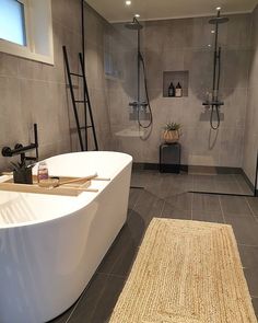 an instagram photo of a bathroom with grey tile and white fixtures, including a large bathtub