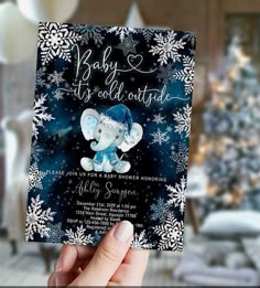 someone holding up a card with an elephant on it in front of a christmas tree