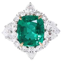 an emerald and diamond ring set in 18k white gold, with diamonds surrounding it