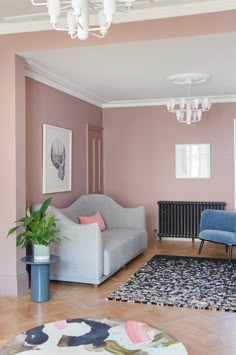 a living room with pink walls and blue furniture in the center, along with a chandelier