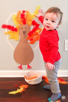 a toddler standing in front of a paper turkey