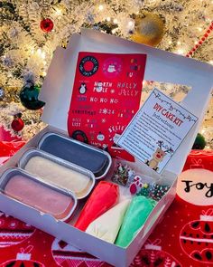 an open box on top of a red table cloth next to a white christmas tree