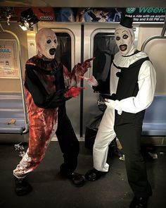 two people in costumes standing next to each other on a subway car, one dressed as a clown and the other as a creepy man