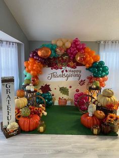 an arch decorated with balloons and pumpkins for a happy thanksgiving sign on the wall