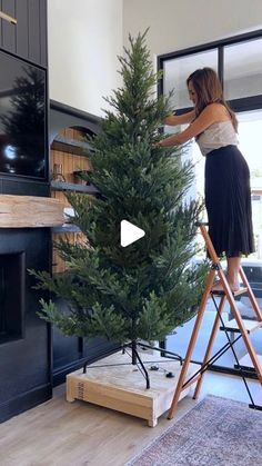 a woman is decorating a christmas tree in her living room