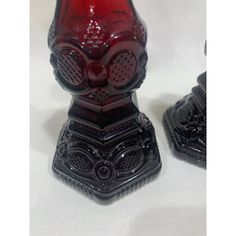 two red glass vases sitting next to each other on a white tableclothed surface