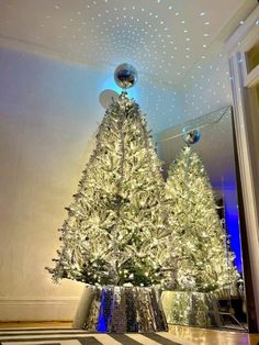 a large christmas tree is lit up in the middle of a room with blue lights