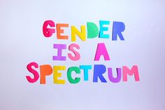 the words gender is a spectrum written in multicolored paper on a white background