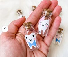 two small bottles with tooth and bow ties on them are in the palm of someone's hand