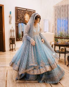 a woman in a blue bridal gown standing on the floor with her hands behind her head