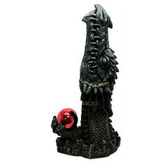 a black dragon figurine with a red ball in its mouth