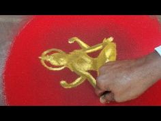 a person is drawing on the ground with gold paint