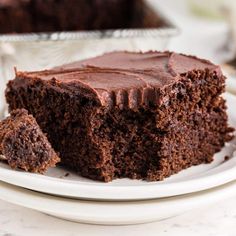 a piece of chocolate cake on a plate with one slice cut out and the other half eaten