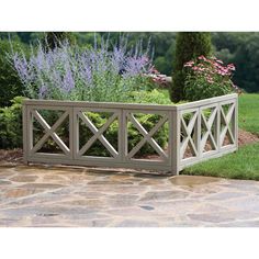 a wooden planter sitting on top of a stone walkway next to a lush green field