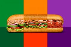 a large sub sandwich with meat and veggies on it in front of a multi - colored background