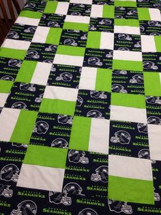 a green and white quilted bedspread with football logos on it