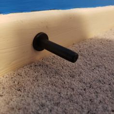 a close up of a black handle on a white and beige carpeted area with blue water in the background