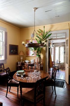 a dining room table with chairs and a potted plant hanging from the ceiling over it