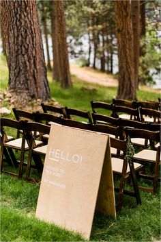 rows of wooden folding chairs with the word hello written on them in front of trees