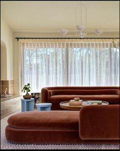 a living room filled with furniture next to a window covered in sheers and curtains