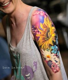 a woman with sunflowers and flowers on her arm is smiling at the camera