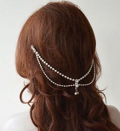 a woman wearing a white head chain with pearls on it's sides and long hair in the back