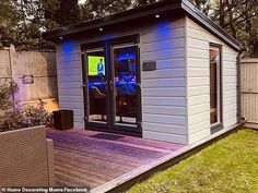 a small backyard shed is lit up with blue lights and sits on a deck in the yard