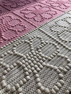 a crocheted blanket is laying on the floor next to a pink and white rug