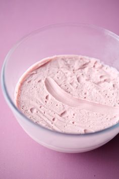 a white bowl filled with cream on top of a pink table