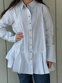 Made from 100% cotton, the Brynlee Ruffle Tunic Shirt is perfect for any season. Its lightweight material and cuffed sleeves provide both comfort and style. The versatile design features a ruffle bottom and can be worn open or closed with buttons down the front. Elevate your wardrobe with this striped must-have! Measurements S: bust 40" length 29" shoulders 15" M: bust 44" length 31" shoulders 16" L: bust 48" length 33" shoulders 17" Cotton Shirt For Spring Daywear, Relaxed Fit Cotton Top With Ruffle Sleeves, Cotton Tops With Ruffle Sleeves In Relaxed Fit, Relaxed Fit Cotton Tops With Ruffle Sleeves, Cotton Tops With Ruffle Sleeve And Relaxed Fit, Cotton Button-up Blouse With Smocked Cuffs, Cotton Blouse With Cuffed Sleeves For Day Out, Trendy Cotton Tops With Smocked Cuffs, Spring Cotton Blouse With Ruffle Sleeves