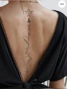 the back of a woman's neck with an intricate tattoo on her lower back