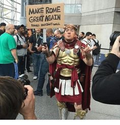 a man dressed in roman armor and holding a sign that says make rome great again