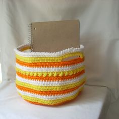 an orange, white and yellow basket with a notepad in it