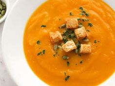 a white bowl filled with carrot soup and croutons