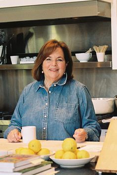 a woman sitting at a kitchen counter with lemons in front of her and books on the counter