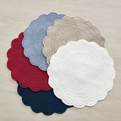 four round placemats in various colors on a table