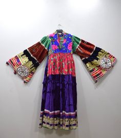 A beautiful Handmade Tribal Kutchi Dress from Afghanistan. Embellished with detailed beading and embroidery this dress has a rich velvet embellished skirt with gold and silver lame, mirrors, beading and embroidery. Kutchi embroidery has approximately 16 different types of stitches and styles and it is these variations that allow for the differentiation between the communities. Embroidery techniques are passed down from mother to daughter. The traditional dress of Afghanistan was very tremendous Bohemian Dresses With Gold Embroidery For Festive Occasions, Traditional Dresses With Multicolor Embroidery And Sequins, Traditional Embellished Velvet Dress, Festive Multicolor Embroidered Embellished Dress, Festive Multicolor Embellished Embroidered Dress, Velvet Bohemian Dress For Holiday Season, Traditional Hand Embellished Multicolor Dresses, Traditional Velvet Dress For Festivals, Festive Embellished Multicolor Dresses