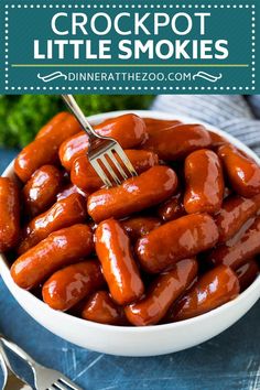 a white bowl filled with hot dogs on top of a blue cloth next to silverware