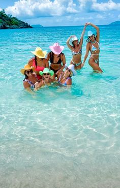 several women in bikinis and hats are standing in the water