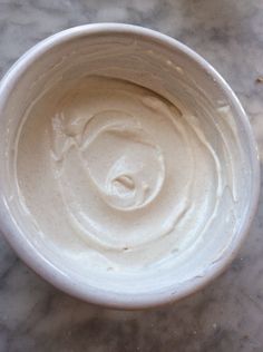 a white bowl filled with cream sitting on top of a table