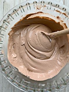 a bowl filled with chocolate frosting on top of a wooden table